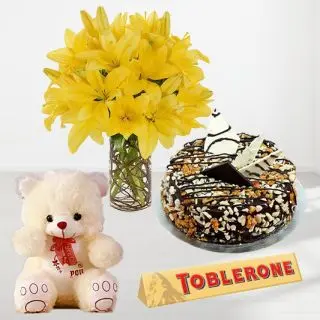 Beautiful yellow lilies in glass vase with dryfruit cake with 1 feet height teddybear with toblerone chocolate 