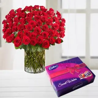 100 Long stem red roses arranged in a glass vase with box of celebration chocolates 