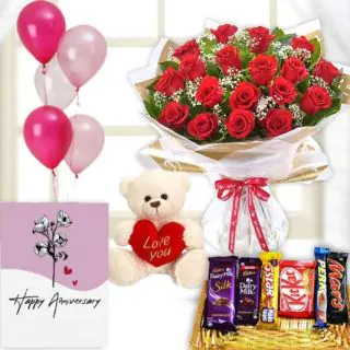 12 red roses bunch , 6 inch teddybear, Basket of assorted chocolates, anniversary Greeting card with 5 blown balloons 
