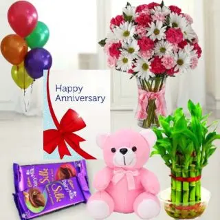 Mix flowers arranged in glass vase, set of 2 dairy milk silk chocolates, 6 inch height teddybear , 2 layer Lucky bamboo plant ,5 blown balloons with anniversary greeting card