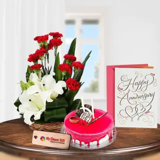 Basket Arrangement of red carnations with white lilies , Half kg strawberry cake with anniversary greeting card 