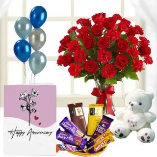 20 red roses with red carnations in glass vase, 1 feet height teddybear, Basket of assorted chocolates ,  anniversary Greeting card with 5 blown balloons 