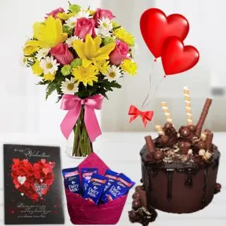 Mix flowers arranged in glass vase, half kg chocolate explosion cake, 2 heart shape balloons , Greeting card, pack of 5 dairy milk chocolates 