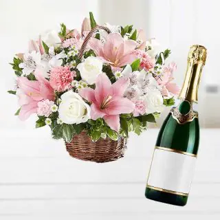 Basket arrangement of white exotic flowers with bottle of champegne