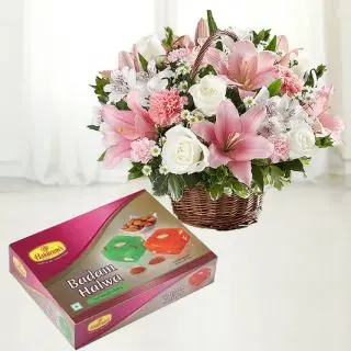 Basket arrangement of lilies and roses with Half kg Badam Halwa