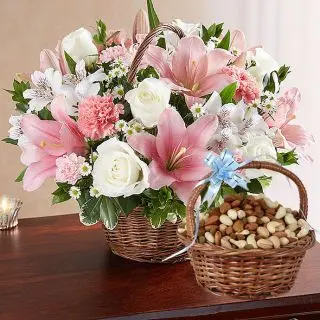 Basket of white lilies with pink roses with basket of assorted dryfruits