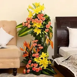 4 feet height Exclusive arrangement of Pink carnations, yellow lilies with Birds of paradise flowers 
