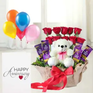 Basket arrangement of 10 roses with 6 dairymilk , with 6 inch teddybear sitting in it, anniversary greeting card with 5 blown balloons 