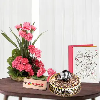 Basket arrangement of 20 pink carnations , half kg butterscotch cake with anniversary card