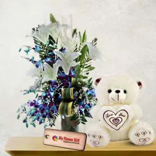 Beautiful Vase arrangement of white lilies with blue orchids with 1 feet height teddy bear 