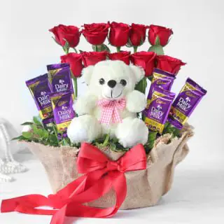 Basket arrangement of 10 red roses, 6 dairy milk chocolates, with 6 inch teddybear sitting in it 