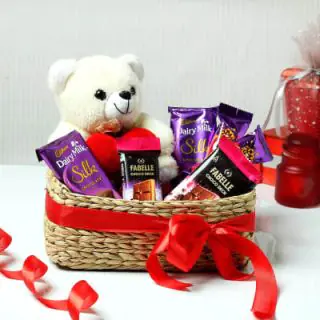 Basket arrangement of 4 dairy milk silk chocolates, 2 fabelle chocolates with 6 inch teddybear sitting in it 