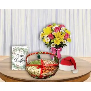 Mix flowers arranged in glass vase, basket of assorted dryfruits, greeting card with santa cap