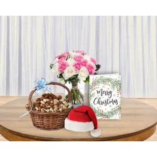 Pink and white roses in glass vase , santa cap, greeting card with basket of assorted dryfruits