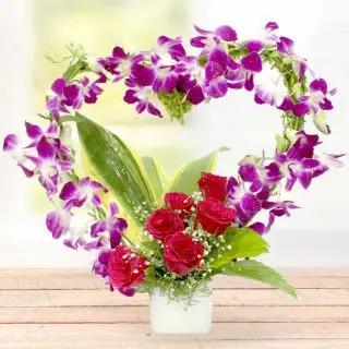Vase arrangement of purple orchids with red roses 