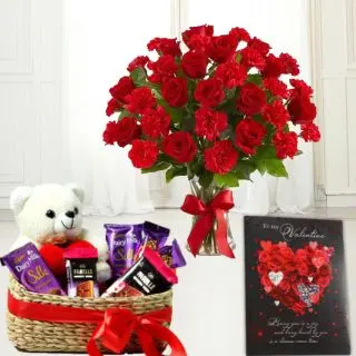 vase arrangement of red roses with red carnations, basket of assorted cadburies with 6 inch teddybear sitting in it with greeting card 
